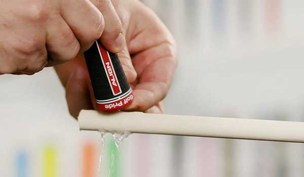 man pouring solvent onto taped shaft before sliding the grip on
