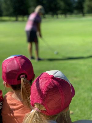 two girls looking at golfer mom at a distance